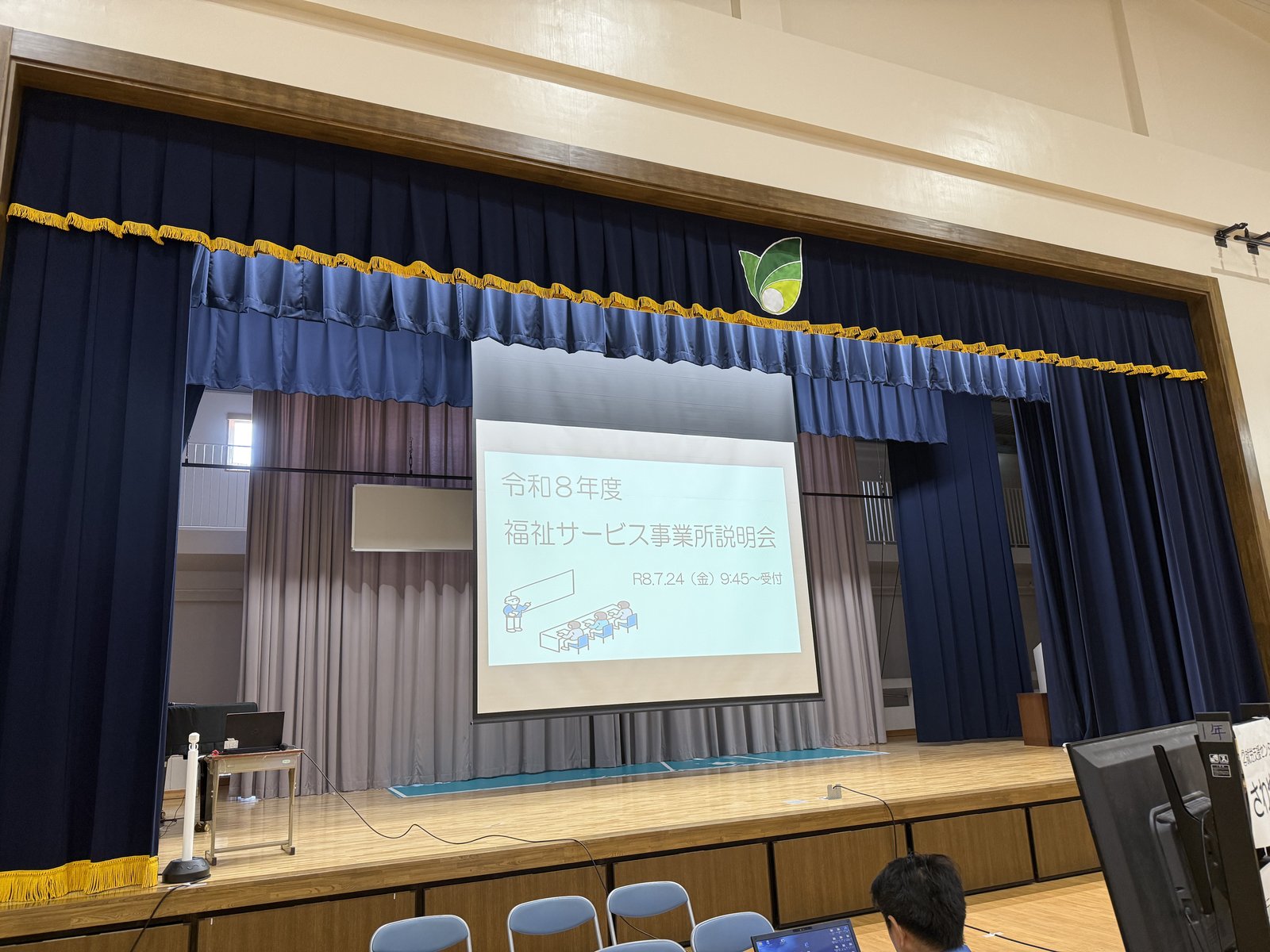 那覇みらい支援学校の体育館ステージに映し出された福祉サービス事業所説明会のタイトル