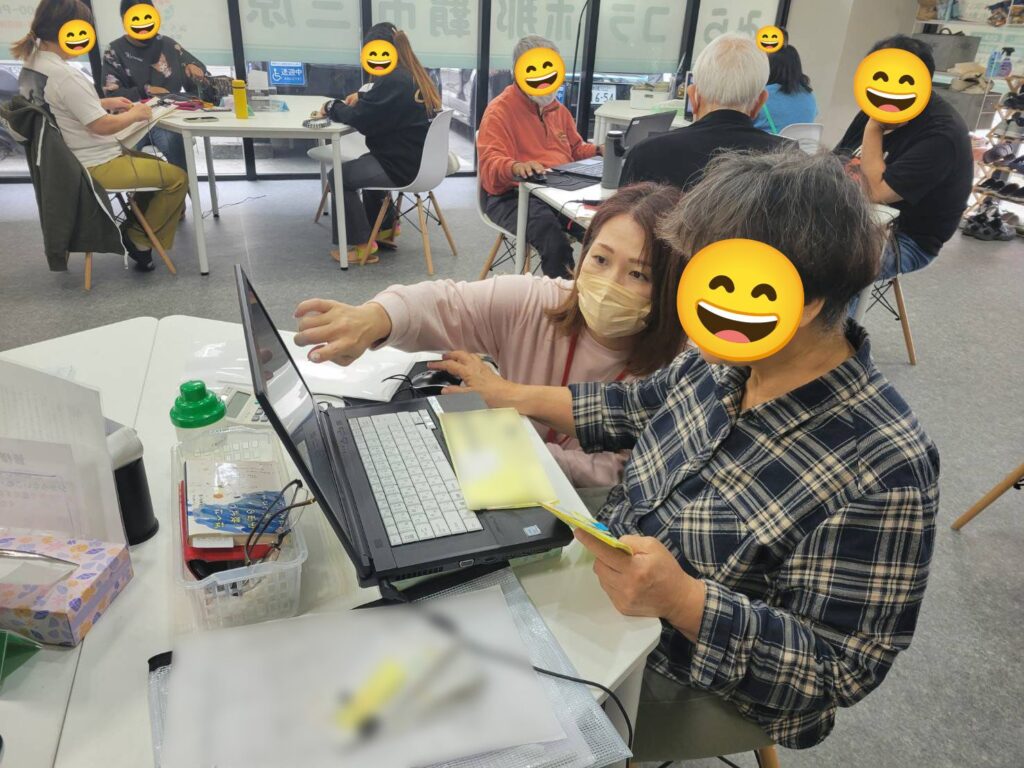 スタッフが利用者さんの隣に座り、パソコンの画面を一緒に見ながら作業を教えている様子
