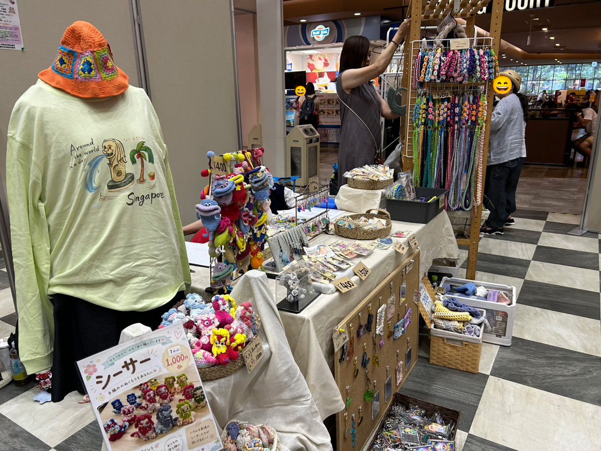 利用者さんのオリジナルイラストをプリントしたTシャツと、手編みの帽子を飾ったみらコラボ国場本店のブース